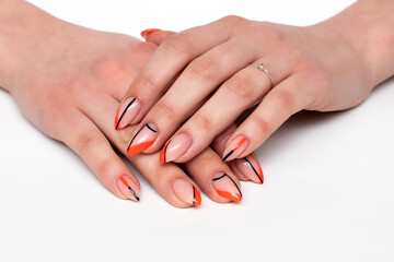 Orange abstraction and black stripes on long sharp nails close-up on white background.