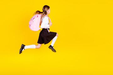 Full body photo of cute little schoolgirl running hurry black friday dressed stylish uniform isolated on yellow color background