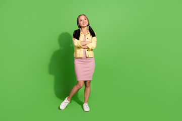 Full body portrait of pretty young woman folded arms look empty space wear jacket dress isolated on green color background