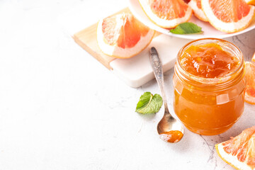 Homemade grapefruit jam, sweet pink grapefruit marmalade in small jar, with grapefruit slices and...