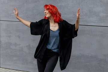 Happy positive emotional dancer curling in dance. Woman with red hair dancing on urban street, on...