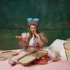 Food ads. Portrait of attractive young woman in period attire sitting on bed with slice of pizza...