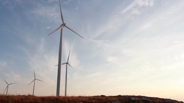  Fazenda de turbinas e&oacute;licas durante o p&ocirc;r do sol ou nascer do sol. Gera&ccedil;&atilde;o de energia livre de emiss&otilde;es com turbina e&oacute;lica. Turbinas e&oacute;licas gerando energia limpa, renov&aacute;vel e sustent&aacute;vel 