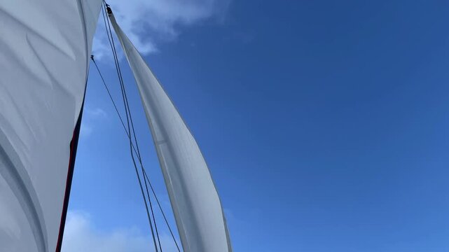 A white sail fluttering in the wind in a clear sky. Low angle view. High quality 4k footage