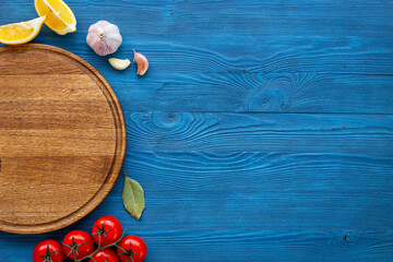 Wooden cutting board and vegetables with spices, top view. Cooking layout