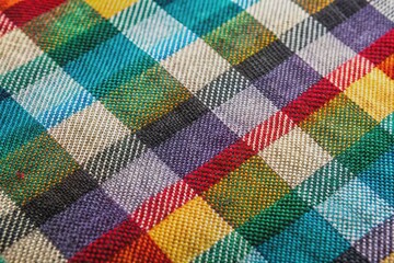Colorful checkered fabric with alternating black and white squares in a tight weave, showing subtle texture and slight thread imperfections in a macro view.