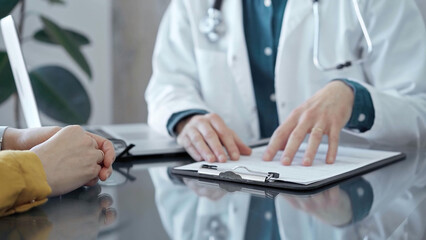 Doctor and patient consultation in clinic. Patient listens attentively as a doctor explains a diagnosis in a modern medical office. Medicine and health care