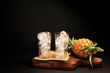 Empty glass with fresh pineapple from the garden Healthy summer food. Cocktails. Natural drinks. Green leaves. Isolated on black background.