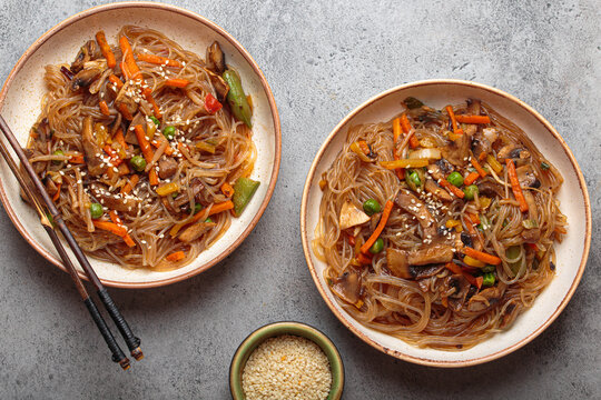 Traditional Korean noodles, two bowls of japchae. A dish featuring sweet potato noodles stir fried with a colorful vegetables and savory meat