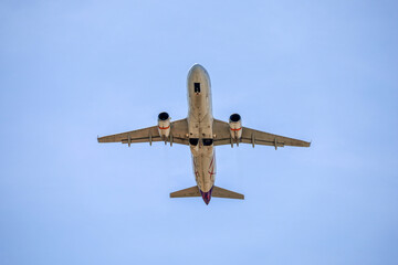 Airplane flying in blue sky, bottom view. Passenger plane at flight, travel concept