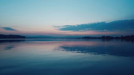 Olympic rings floating serenely above a calm, reflective lake at dusk, casting gentle reflections on the water's surface. 