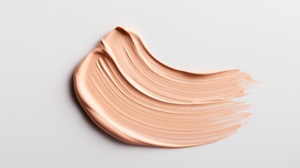 Smooth application of warm beige foundation on a white surface in natural light.
