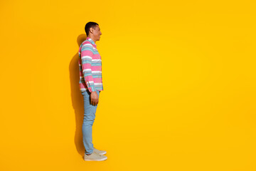 Full size photo of pretty young male profile look empty space wear trendy striped outfit isolated on yellow color background