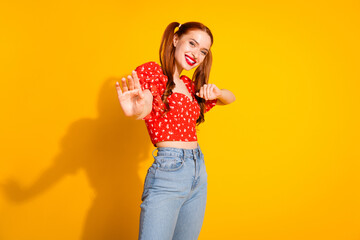 Photo portrait of young red hair funky positive girl wearing blouse and jeans dancing invite you party isolated on yellow color background