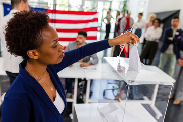 African American voter placing ballot in ballot box polling place in America