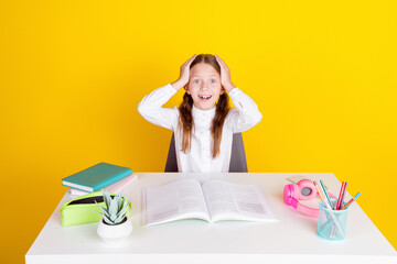 Photo portrait of charming little pupil girl shocked impressed do homework wear trendy uniform isolated on yellow color background