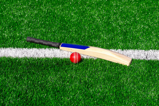 Cricket bat and red ball with natural lighting on green grass. Horizontal sport theme poster, greeting cards, headers, website and app