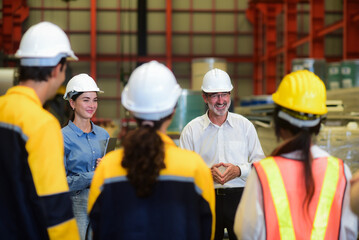 Happy professional Caucasian senior engineer is training industry worker, machine operator, mechanical engineering team in heavy industrial manufacture factory Before starting work in the morning.