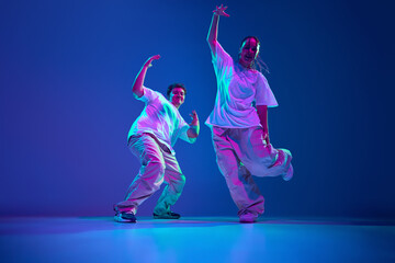 Dynamic image of artistic and energetic young man and woman, dancers performing hip-hop against...