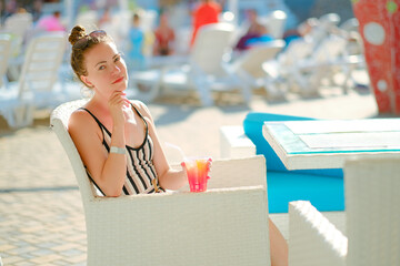 Girl with cocktail sitting in chair by pool