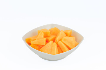 Slices of a melon in a white bowl isolated on white background.