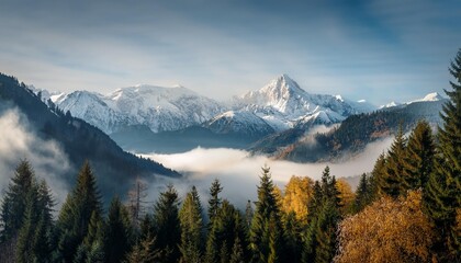 Obraz premium Majestic mountain range with snow-capped peaks and trees, enveloped in a thick mist.
