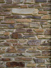 Close up design texture showing a section of wall constructed with variegated rock bricks, of different sizes, and a multitude of different natural colours.