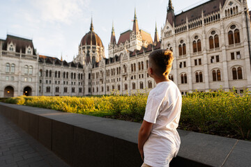 Obraz premium Boy admiring majestic European architecture at sunset in Budapest, Hungary.