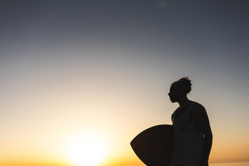 Fototapeta premium unrecognizable A man is standing on a beach holding a surfboard