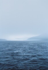 Naklejka premium High-Quality Vertical Minimalist Ocean Landscape with Misty Mountains - Ideal for Nature Photography and Wall Art