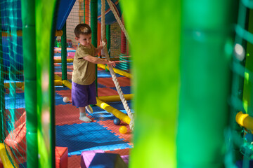 Child playing in colorful indoor playground with climbing ropes. Indoor playground photography for...