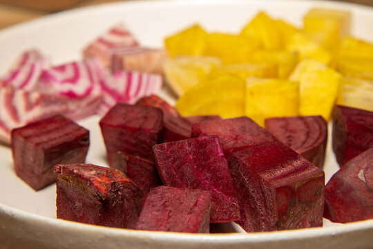 A plate of chopped up ingredient ready to make a delicious meal consisting of Fresh yellow and pink and white chioggia beets - Powered by Adobe