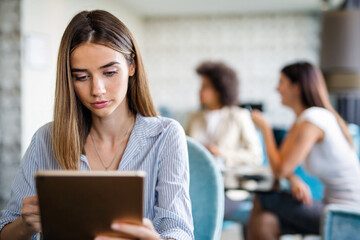 Obraz premium Young happy successful business woman working with tablet in corporate office