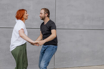 Happy dancers curling in dance in city. Romantic couple, woman with red hair and man in dark...