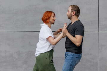 Happy dancers curling in dance in city. Romantic couple, woman with red hair and man in dark...