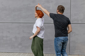 Happy dancers curling in dance in city. Romantic couple, woman with red hair and man in dark...