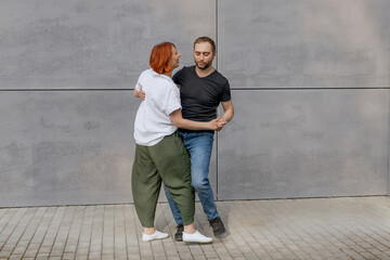 Happy dancers curling in dance in city. Romantic couple, woman with red hair and man in dark...