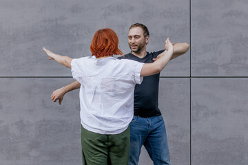 Happy dancers curling in dance in city. Romantic couple, woman with red hair and man in dark...