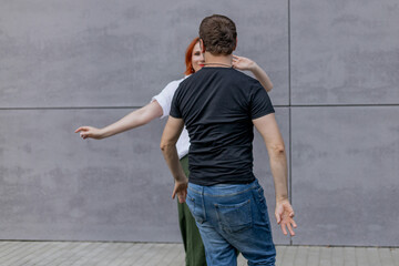 Happy dancers curling in dance in city. Romantic couple, woman with red hair and man in dark...