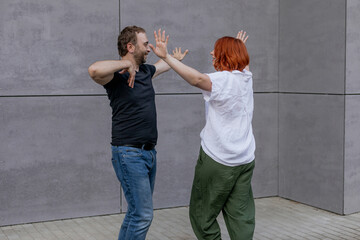 Happy dancers curling in dance in city. Romantic couple, woman with red hair and man in dark...
