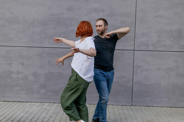 Happy dancers curling in dance in city. Romantic couple, woman with red hair and man in dark...