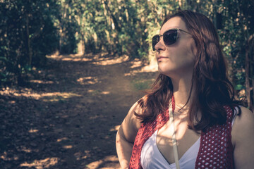 Brazilian woman with sunglasses, enjoys the sun when she take a walk in the Botanical garden. Jardim Botanic Garden, São Paulo, Brazil.