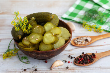 Bowl of tasty pickled cucumbers with spices and dill on light background. Marinated homemade pickled cucumbers. Healthy fermented food.
