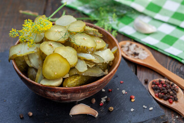 Bowl of tasty pickled cucumbers with spices and dill on wooden background. Marinated homemade pickled cucumbers. Healthy fermented food.