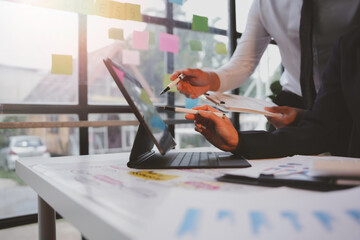 Business partners reviewing data on a digital tablet and brainstorming in a bright office