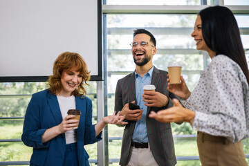Group of multicultural colleagues standing in the conference room and having coffee break.