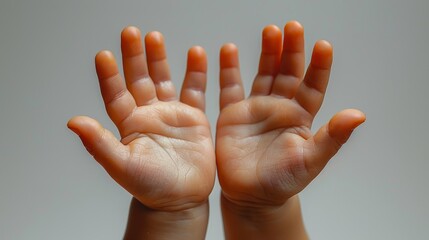 Two small baby hands reaching up with open palms against a light gray background