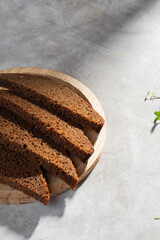 Black rye bread is cut into portions and lies on a wooden plate
