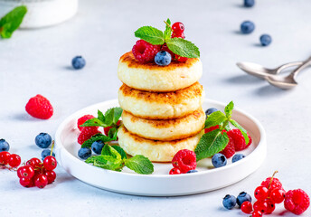 Thick pancakes with cottage cheese and berries with mint for yummy breakfast. Gray table background