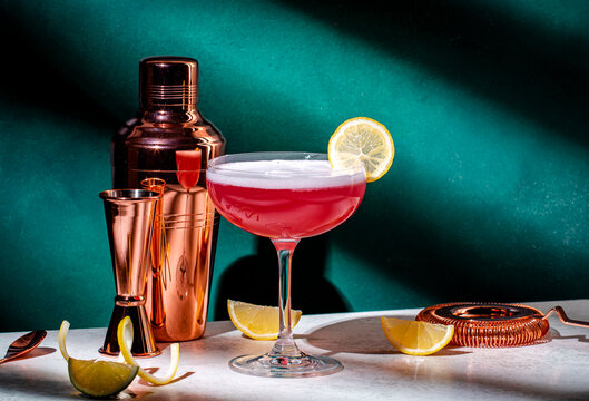 Pink alcoholic cocktail drink with gin, grenadine syrup, lemon juice and egg white, dark green background